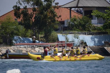 Bali, Endonezya - 19 Eylül 2012: Tanjung Benoa plaj ziyaretçileri muz teknesine binerek tatilin tadını çıkarıyorlar.