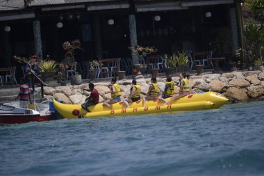 Bali, Endonezya - 19 Eylül 2012: Tanjung Benoa plaj ziyaretçileri muz teknesine binerek tatilin tadını çıkarıyorlar.