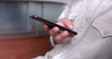 Beyaz gömlekli adam modern parlak ofiste çalışıyor, akıllı telefon kullanıyor, günlük gömlekli işletme sahibi telefonu tutuyor, internet sayfalarını tarıyor..