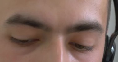 Extreme close-up, shifty eyes of a European guy with a headset on his head, busy with work, communicating with a client. Support service concept.