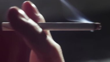 Aşırı yakın plan, adam sigarayı dudaklarına götürür ve dumanı içine çeker, adam yakın plan sigara içer.