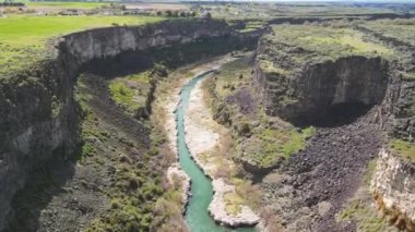 Idaho 'daki Hansen Köprüsü manzaralı. Her iki tarafında kayalıklar olan yeşil bitki örtüsü ve su var.