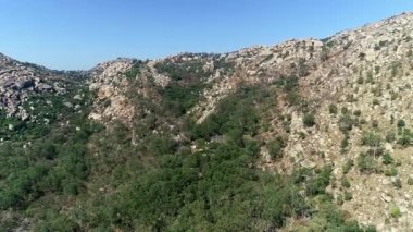 Orman ağaçları ve kaya kayaları arasındaki gizli tarihi tapınağın hava izleme görüntüsü.