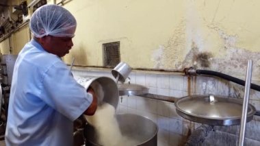 Bangalore, Hindistan-13 Mayıs 2016: Pirinç hazırlamak için sıcak buhar teknesine pirinç döken bir adam. Yemek pişirme süreci. Buhar donanımı. Fabrika