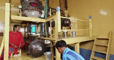 Mysore,India-June 20,2016:Closeup of worker taking out raw oil from tank inside the factory for quality check