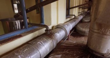 Closeup of big pipes and valves connected to the boilers inside the factory