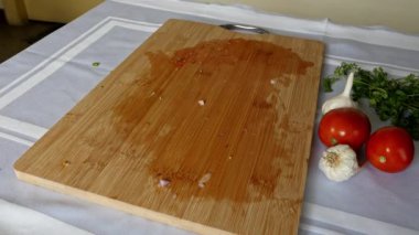 Closeup of used wooden chop board lying on the table after cutting the vegetables