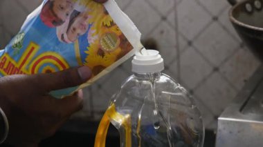 Bangalore,India-December 31,2022: Closeup shot of refined cooking oil from plastic bag poured into plastic container inside the kitchen