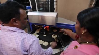 Kaiwara,Chikkaballapura,India-January 5,2017:A closeup of workers using an automatic machine to make chapati or flatbread at boarding school