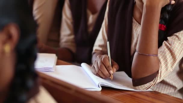 教室内に鉛筆で机の上にノートを書いている女子学生の手を閉じる — ストック動画