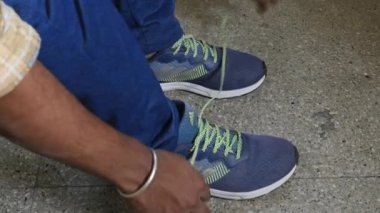 Closeup of hands tying up laces of shoes on floor inside the house