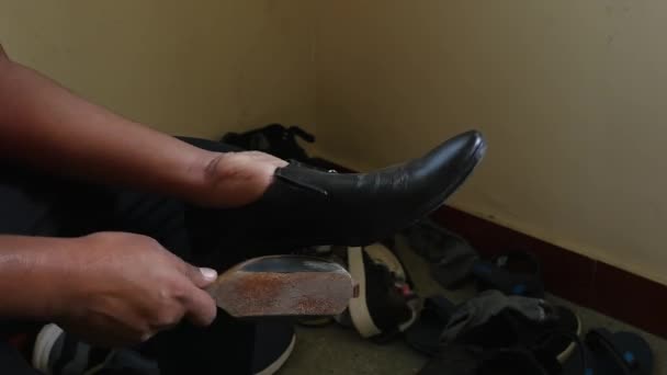 インド人の学士が家の中で黒い靴を磨き — ストック動画
