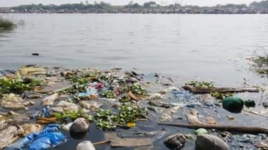 A close-up of a trash-filled river during a Hindu religious event.mailaralingeshwara karnika