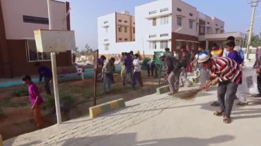 Kaiwara,Chikkaballapura,India-January 6,2017:Group of male students working together to clean up the school campus during a sunny morning