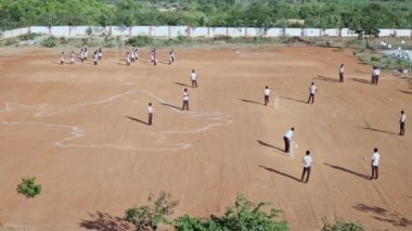 Top view of schoolchildren playing on the playground during a sunny day at a rural school