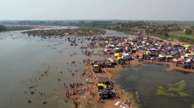 Hindu dini festivali karnikotsava (kehanet) sırasında nehir kıyısında kamp kuran büyük bir insan kalabalığının havadan görüntüsü.