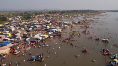 Hindu dini festivali karnikotsava (kehanet) sırasında nehir kıyısında kamp kuran büyük bir insan kalabalığının havadan görüntüsü.