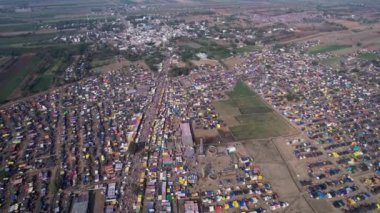 Hindu dini festivali karnikotsava sırasında tarlalarda barınan renkli çadırlar, dükkanlar ve dindarlarla dolu kalabalık bir kasaba fuarının hava görüntüsü. (Kehanet)
