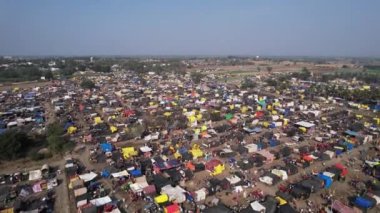 Hindu dini festivali karnikotsava sırasında tarlalarda barınan renkli çadırlar, dükkanlar ve dindarlarla dolu kalabalık bir kasaba fuarının hava görüntüsü. (Kehanet)