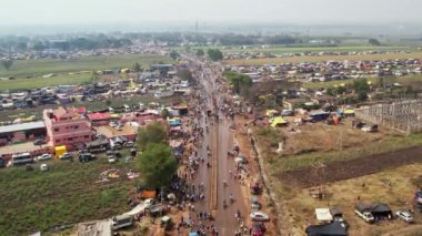 Aerial track view of huge crowded road with huge tents and shelters in farmlands during the Hindu religious annual fair
