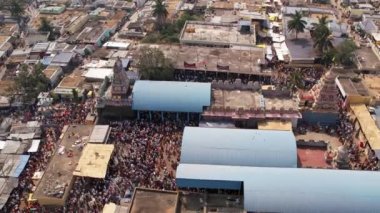 An aerial view of a crowd of people and a temple in the middle of a village during a Hindu religious annual festival
