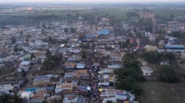 Aerial video of a massive crowd moving on a busy road towards the temple during a religious event, karnikotsava, or prophecy