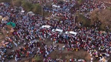 Vijayanagara,India-February 7,2023:Aerial top view of white cars moving slowly between the crowd of people during hindu religious event