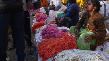 Bangalore,India-February 12,2023:Closeup of women vendors selling colorful flower garlands in the market during mornings