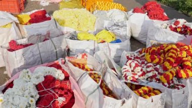 A close-up of the bright flower garlands in the large carry bags in the flower market for sale