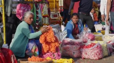 Bangalore,India-February 12,2023:Close view of women packing flowers in a plastic bag for a customer at flower market