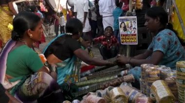 Vijayanagara,India-February 7,2023:A woman is seen adorning a customer's hand with bangles inside the annual fair in india
