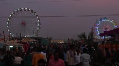 Vijayanagara,India-February 7,2023:A view of the giant wheel or ferris wheel and crowd of people during night at an Indian hindu religious annual festival fair