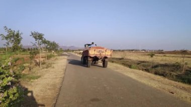 Vijayanagara,India-january 19,2023:A view of a tractor transporting soil on a country village road during a sunny day