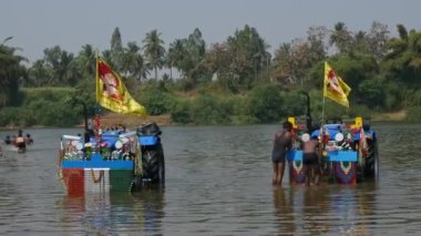 Vijayanagara,India-February 5,2023:A video of men washing the tractors in the river water during the religious festival