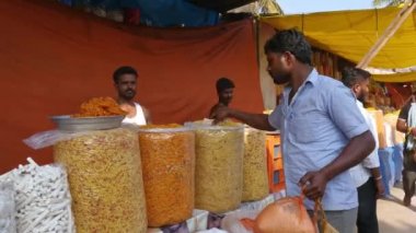 Vijayanagara,India-February 5,2023:Customers were seen purchasing spicy snacks at a festival fair during sunny day