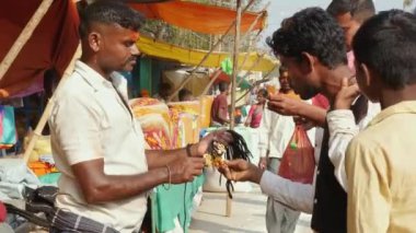 Vijayanagara,India-February 5,2023:A video of people purchasing lockets at the roadside at a festival fair during sunny day
