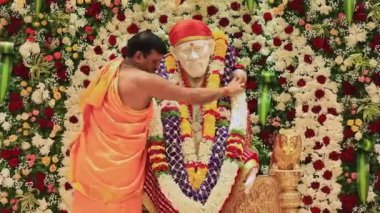 Tumkur,India-July 13,2022:Closeup of a priest putting flower garlands on the Sai Baba idol during religious event