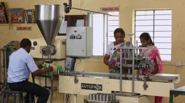 Bangalore, Hindistan-Nisan 6 2016: Bir fabrikadaki yarı otomatik dolum makinesinde çalışan bir işçi tarafından şişelere hindistan cevizi yağı dolduruluyor