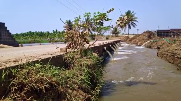 道路橋の下のパイプから汚れた水の小川灌漑用の小さな水路 — ストック動画