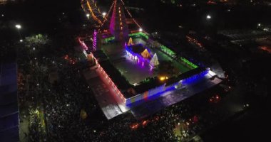 Işık süslemeleri olan bir tapınağın havadan gece görüşü ve bir grup insan Hindu dini etkinliğini kutlamak için bir araya geldi.