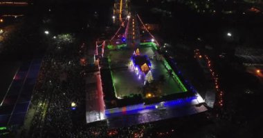 Işık süslemeleri olan bir tapınağın havadan gece görüşü ve bir grup insan Hindu dini etkinliğini kutlamak için bir araya geldi.