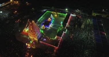 Işık süslemeleri olan bir tapınağın havadan gece görüşü ve bir grup insan Hindu dini etkinliğini kutlamak için bir araya geldi.