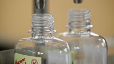 Bangalore, Hindistan-11 Mayıs 2016: Sabun üretim ünitesi içindeki bir dolgu makinesi tarafından şişelere doldurulan bitkisel el yıkamaya yakından bakmak