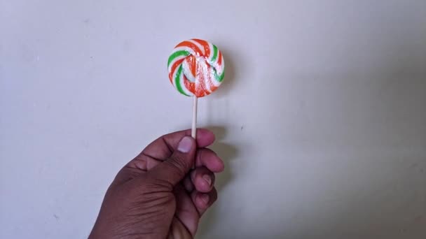 Closeup Hand Holding Colorful Swirl Lollipop Rotating Slowly Front Camera — Stock Video