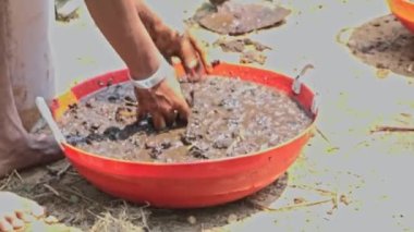 Tohum toplarını hazırlamak için verimli toprak ve gübreyi plastik bir kabın içinde suyla karıştıran çıplak ellerin yakın çekimi. Çevresel kavram. Yeşil toprak kavramı.