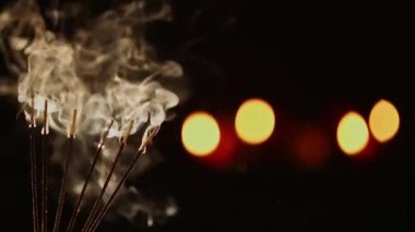 Siyah bulanık arkaplan üzerine tütsü tütsüsü tüttüren sinematik bir video. Reklam kavramı. Tütsü çubukları.