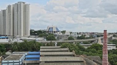 Bir yaz günü arkaplanda ISKCON tapınağı ve gökdelenlerle demiryolu raylarında hareket eden metro treninin sinematik görüntüsü