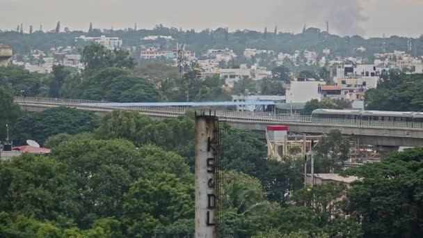 インド バンガロール2016年7月25日 バンガロール市内を背景に工場の煙突の煙と橋を渡る地下鉄の列車の眺め — ストック動画