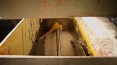 Bir fabrika işçisi torbayı keser ve sabun malzemelerini karıştırıcıya döker. sabun üretimi. Sabun fabrikasındaki makineler