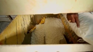Erkek eller torbayı bıçakla keser ve sabun malzemelerini karıştırıcıya döker. sabun üretimi. Sabun fabrikasındaki makineler